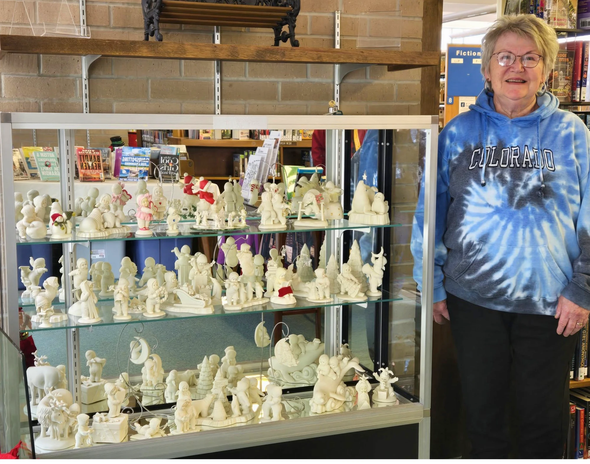 An adult standing next to a display case of ceramic figurines.
