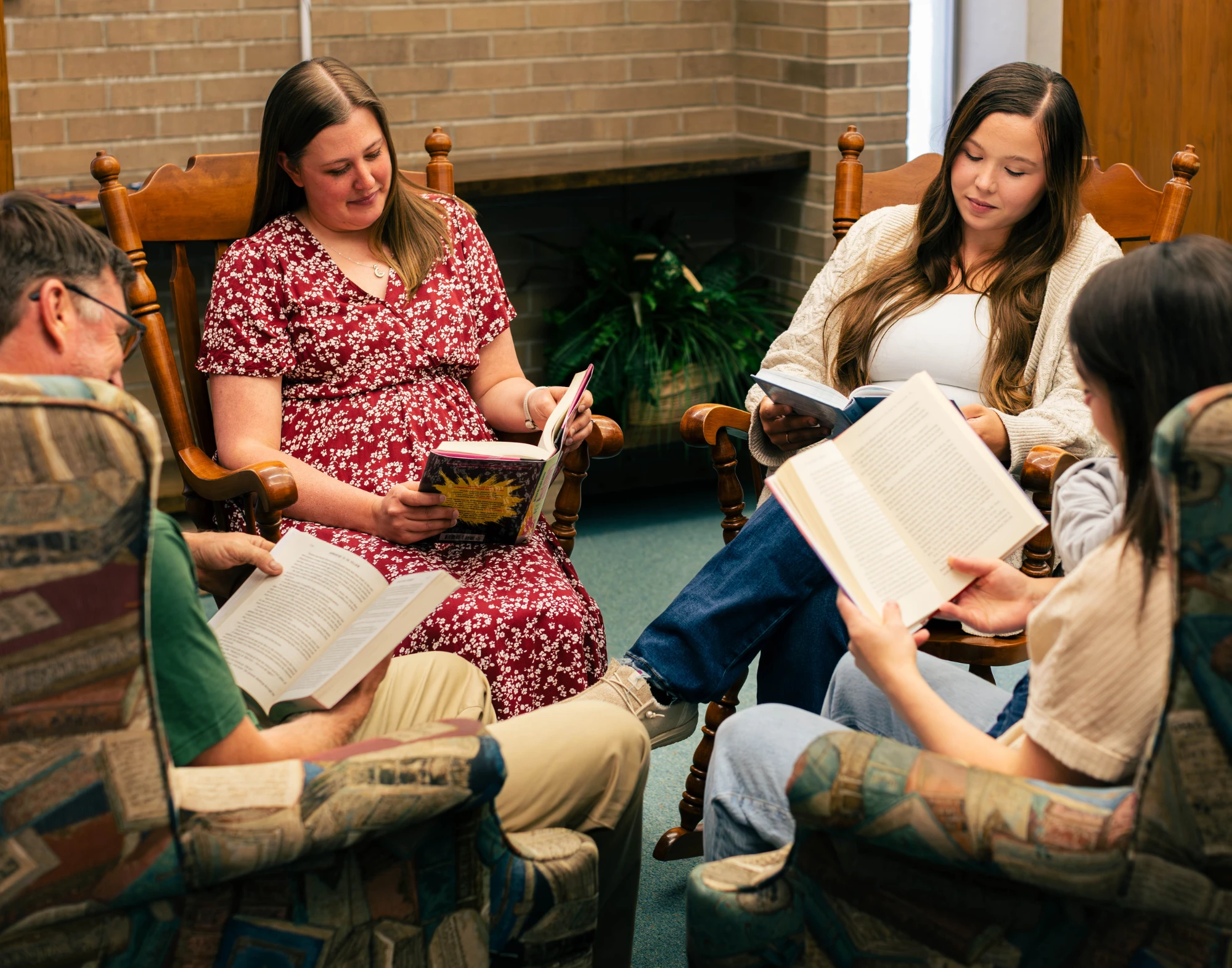 Four seated adults reading books together in a circle.