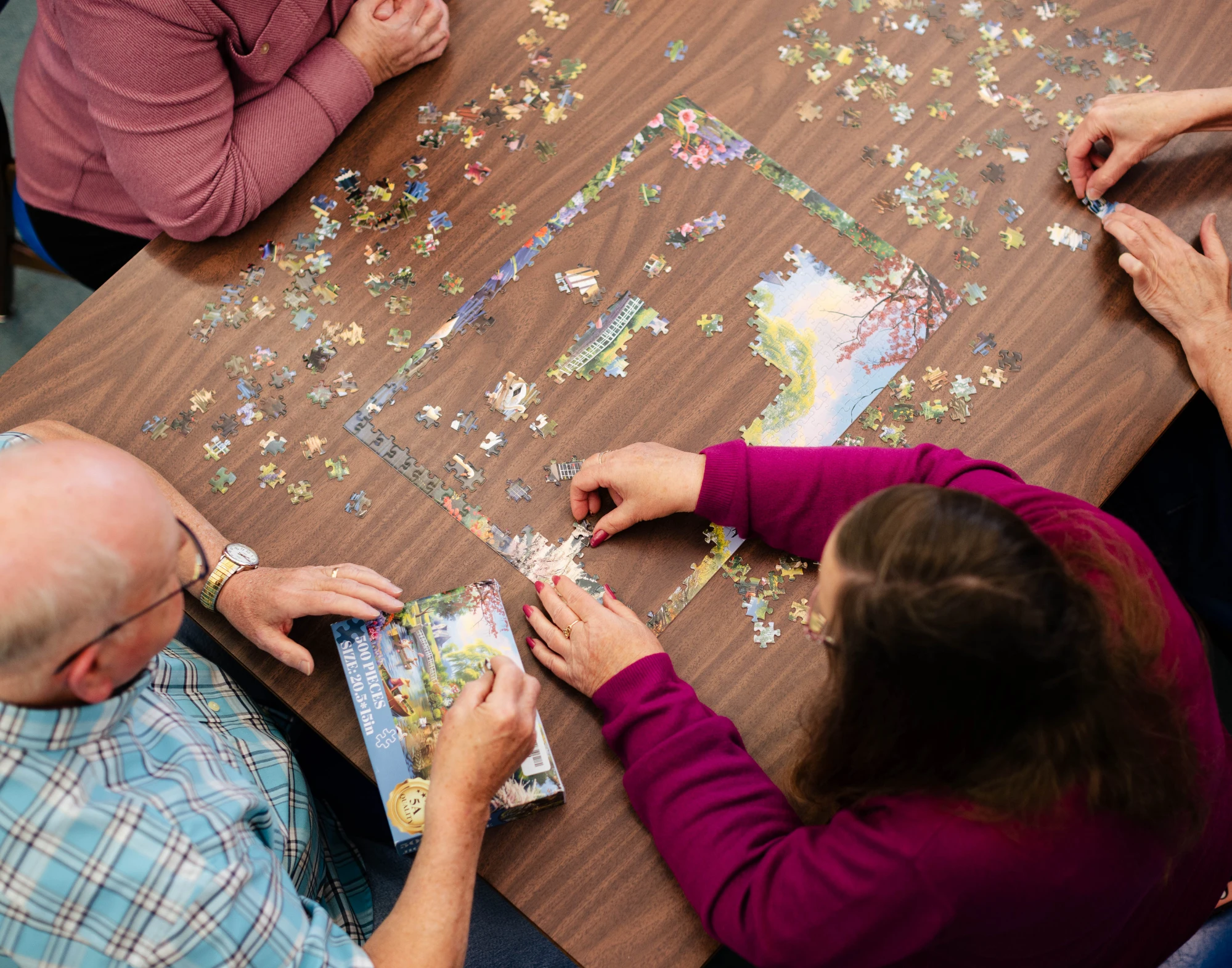 Four adults putting together a jigsaw puzzle on a table.