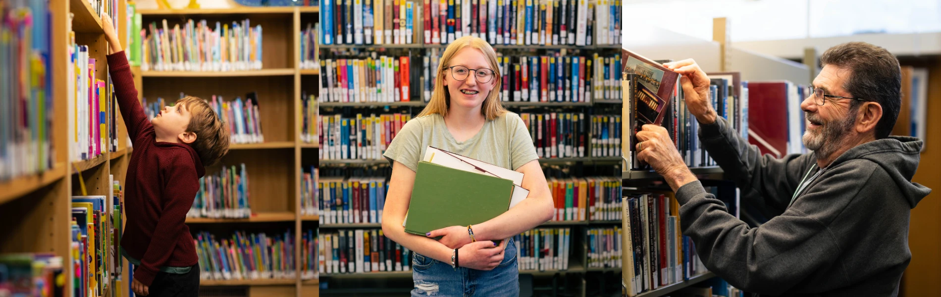 Three people stand in a library with bookshelves in the background, holding or reaching for books.